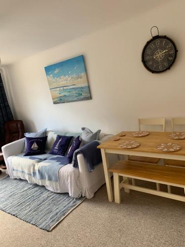ein Wohnzimmer mit einem Sofa und einem Tisch in der Unterkunft Lovely well equipped apartment - 2 bedroom, sleeps 4, sundeck, 8 min river walk to beach and town, FREE parking permit ! in Lyme Regis