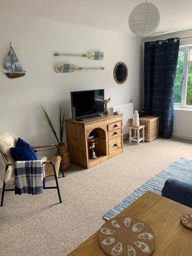 a living room with a television and a table at Lovely home from home apartment 8 mins walk to beach with free parking and sun deck 2 bed sleeps 4 in Lyme Regis
