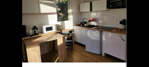 uma cozinha com armários brancos e um micro-ondas em Jolies Appartement 6 couchages a praloup 1600 avec balcons em Uvernet