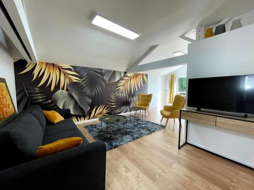 ein Wohnzimmer mit einem Sofa und einem Flachbild-TV in der Unterkunft Gîte de la fauvette SAINTES in Saintes
