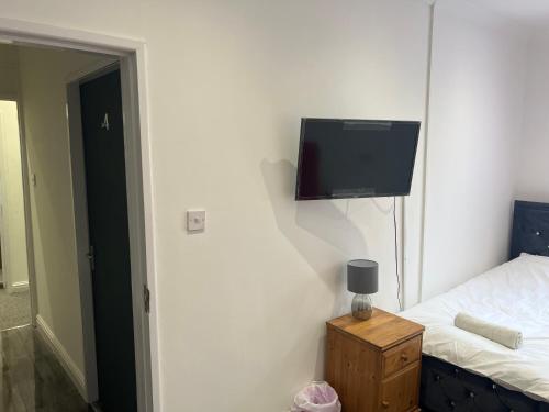 a bedroom with a bed and a flat screen tv on the wall at Zams rooms in Stoke on Trent