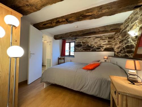 a bedroom with a bed and a stone wall at Le Mas Bertrand in Villefranche-de-Panat