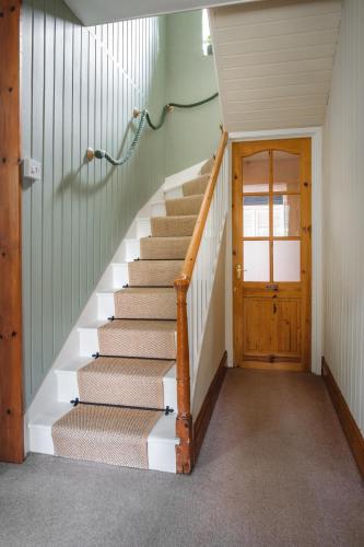 a staircase in a house with a wooden door at The Green Door Vegan B&B in Llanon