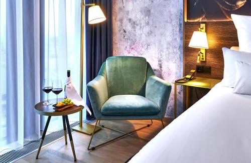 a bedroom with a bed and a chair and a table at NYX Hotel Warsaw by Leonardo Hotels in Warsaw