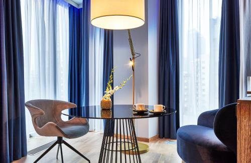 a room with a table and a chair and a lamp at NYX Hotel Warsaw by Leonardo Hotels in Warsaw