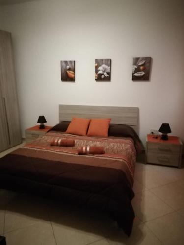 - une chambre avec un grand lit et des oreillers orange dans l'établissement San Anton Studio Apartment, à Taʼ Sardina