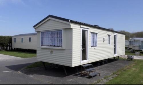 a white tiny house parked in a parking lot at Caravan Sleeps 4 with Free Parking in Burnham on Sea