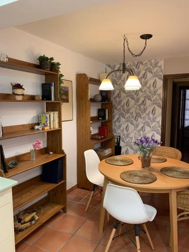 a kitchen with a wooden table and white chairs at La Casa de Baix in Torre del Compte