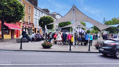 a crowd of people walking down a street with a large white tent at Cozy Cottage Retreat in Listowel pet friend in Listowel