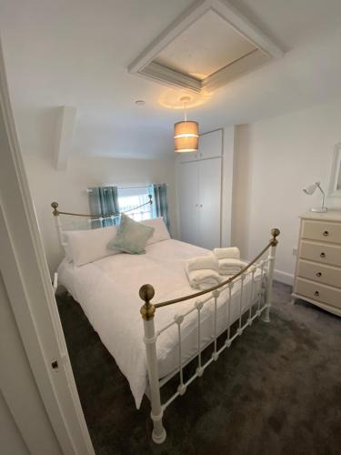 a bedroom with a white bed and a dresser at The Cottage in Ystradgynlais