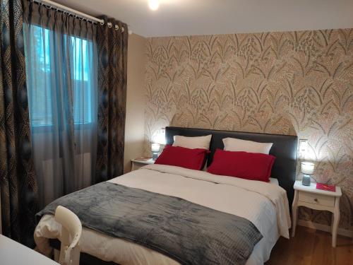 une chambre avec un grand lit avec des oreillers rouges dans l'établissement Le Clos des Feugrais - Calme & Confort, à Saint-Aubin-lès-Elbeuf