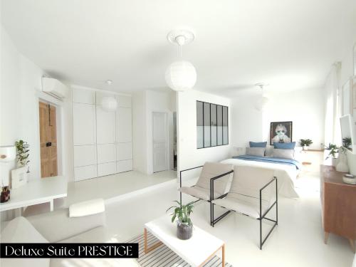 a white room with a bed and chairs in it at Le Prince - Maison d'hôtes in Marseillan