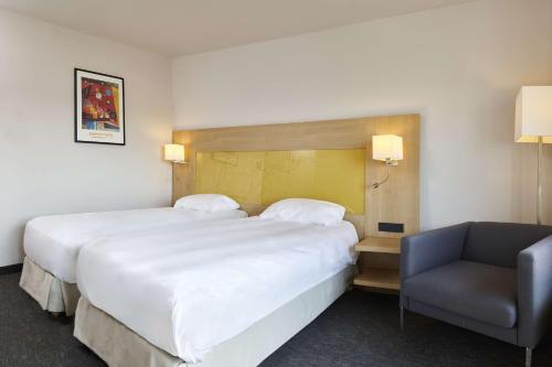 a bedroom with a large white bed and a chair at Park Inn by Radisson Liege Airport in Liège