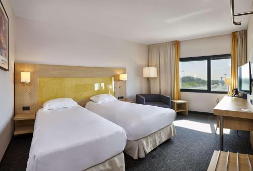 a hotel room with two beds and a desk at Park Inn by Radisson Liege Airport in Liège