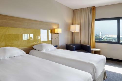 a hotel room with two beds and a chair at Park Inn by Radisson Liege Airport in Liège