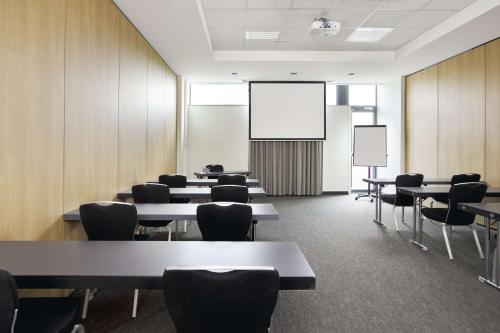 a conference room with tables and chairs and a screen at Park Inn by Radisson Liege Airport in Liège