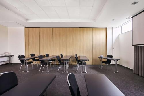 a conference room with tables and chairs and a projection screen at Park Inn by Radisson Liege Airport in Liège