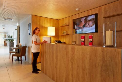a woman standing at a counter in a hotel room at H4 Hotel München Messe in Munich