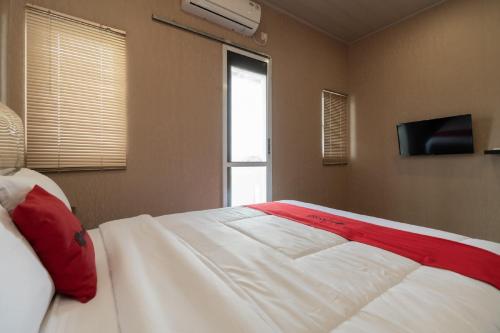 a bedroom with a large white bed with red pillows at RedDoorz @ Jalan Srikandi Pekanbaru in Parit