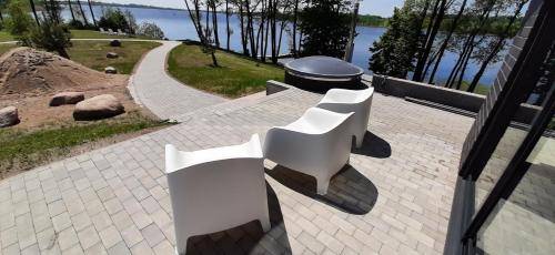 a group of white benches sitting on a brick patio at Vila Galadusis prie ežero in Lazdijai