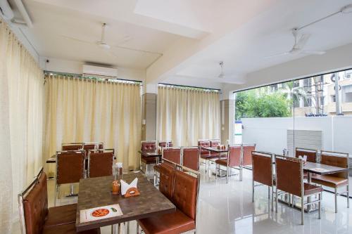 a restaurant with tables and chairs and a large window at FabHotel Limestone Suites -750M from Yashoda Hospitals, Somajiguda in Hyderabad