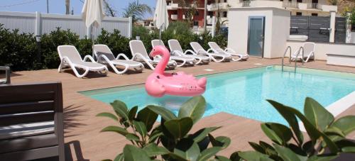 a swimming pool with chairs and a pink inflatable flamingo at Valenti rooms & relax in Villaggio Mosè