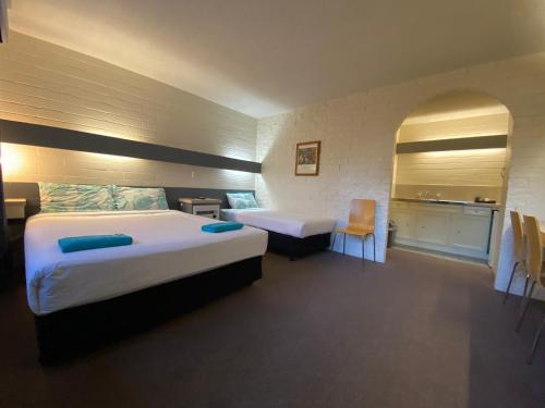 a hotel room with two beds and a kitchen at Mahogany Motel Warrnambool in Warrnambool