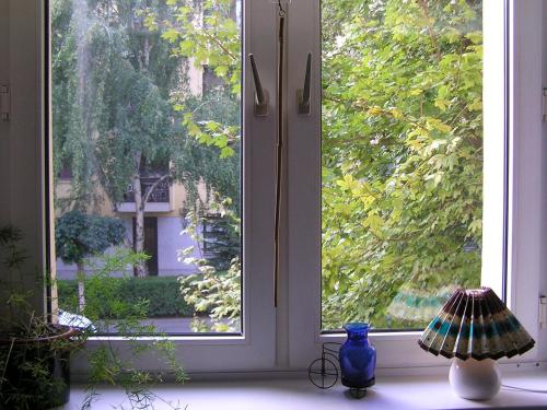 a window with a blue vase and a lamp on a window sill at Belvárosi Studio Apartman in Győr