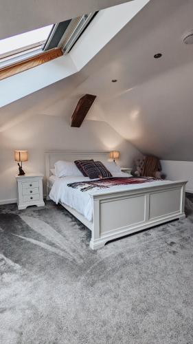 a bedroom with a white bed in a attic at Bluebell Copse Cottages New Forest with Hot Tub in Southampton
