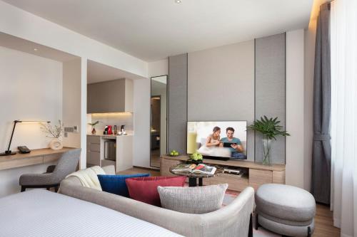 a living room with a couch and a tv at Ascott Embassy Sathorn Bangkok in Bangkok