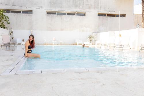 a woman in a bikini sitting in a swimming pool at La Gemma del Salento Rooms&Apartments in Racale