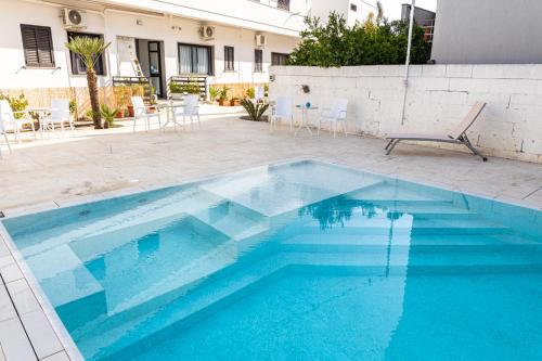 a swimming pool with blue water in front of a house at La Gemma del Salento Rooms&Apartments in Racale