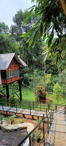 a tree house in a park next to a fence at Santhi Hill View Resort in Munnar