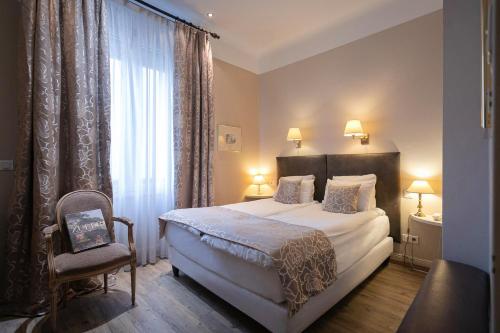 a bedroom with a bed and a chair and a window at Grand Hôtel Bristol in Colmar