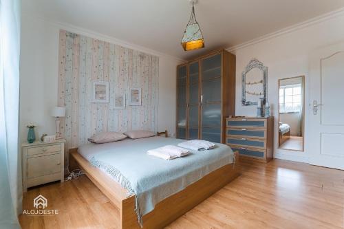 um quarto com uma cama, uma cómoda e um espelho em Casa do Avô Zé - Silveira - Santa Cruz em Santa Cruz