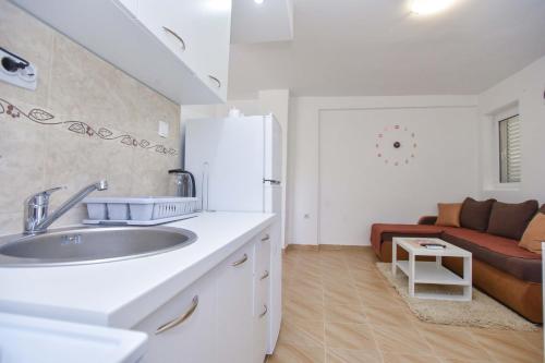 Ban Apartmani في بودفا: مطبخ أبيض مع حوض وأريكة