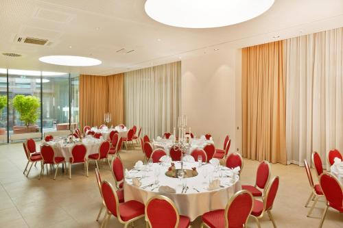 a conference room with white tables and red chairs at H4 Hotel München Messe in Munich