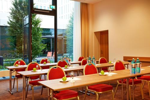 a restaurant with wooden tables and red chairs at H4 Hotel München Messe in Munich