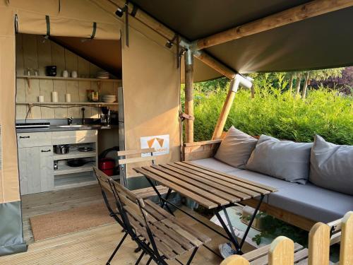 eine Terrasse mit einem Sofa und einem Tisch sowie eine Küche in der Unterkunft 'Glamping' Angelzelt am See mit Steg und Boot (Mecklenburger Seenplatte) in Blankensee