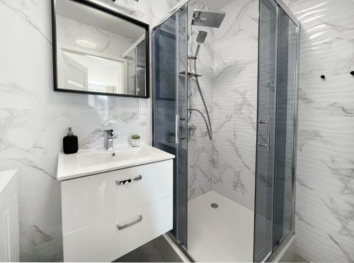 a bathroom with a shower and a sink and a mirror at Przytulny apartament 500m od morza. in Gdańsk