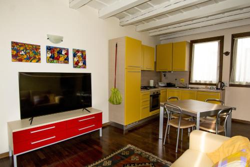 eine Küche mit gelben Schränken und einem Tisch mit einem TV in der Unterkunft Residence dei Frutti pieno centro - Il Ribes in Padua