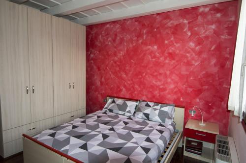 ein Schlafzimmer mit einem Bett und einer roten Wand in der Unterkunft Residence dei Frutti pieno centro - Il Ribes in Padua