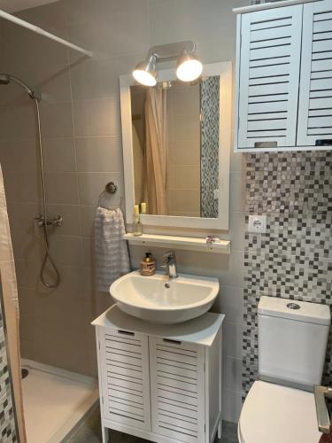 Un baño con lavabo, inodoro y espejo. en El Salvador, en Cuenca