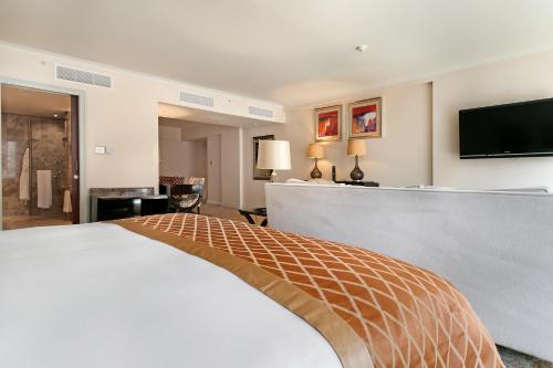 a hotel room with a bed and a flat screen tv at Taj Executive Suites, Private Residence in Cape Town