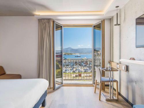 a hotel room with a bed and a view of the ocean at ibis Styles Ajaccio Napoleon in Ajaccio