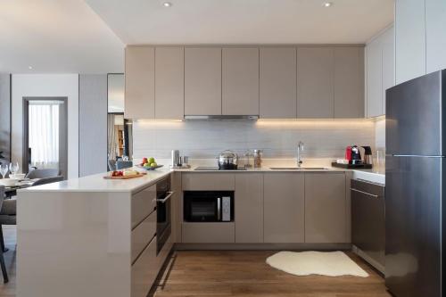 a kitchen with white cabinets and stainless steel appliances at Ascott Embassy Sathorn Bangkok in Bangkok