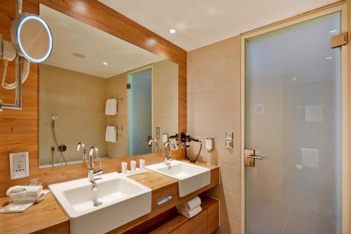 a bathroom with two sinks and a shower at H4 Hotel München Messe in Munich