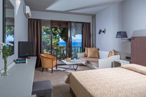 a hotel room with a bed and a living room at Aeolos Beach Resort in Gastouri