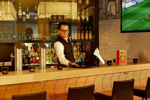 
a man sitting at a bar with a glass of wine at H4 Hotel München Messe in Munich

