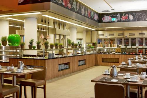 a restaurant with wooden tables and chairs and a counter at H4 Hotel München Messe in Munich